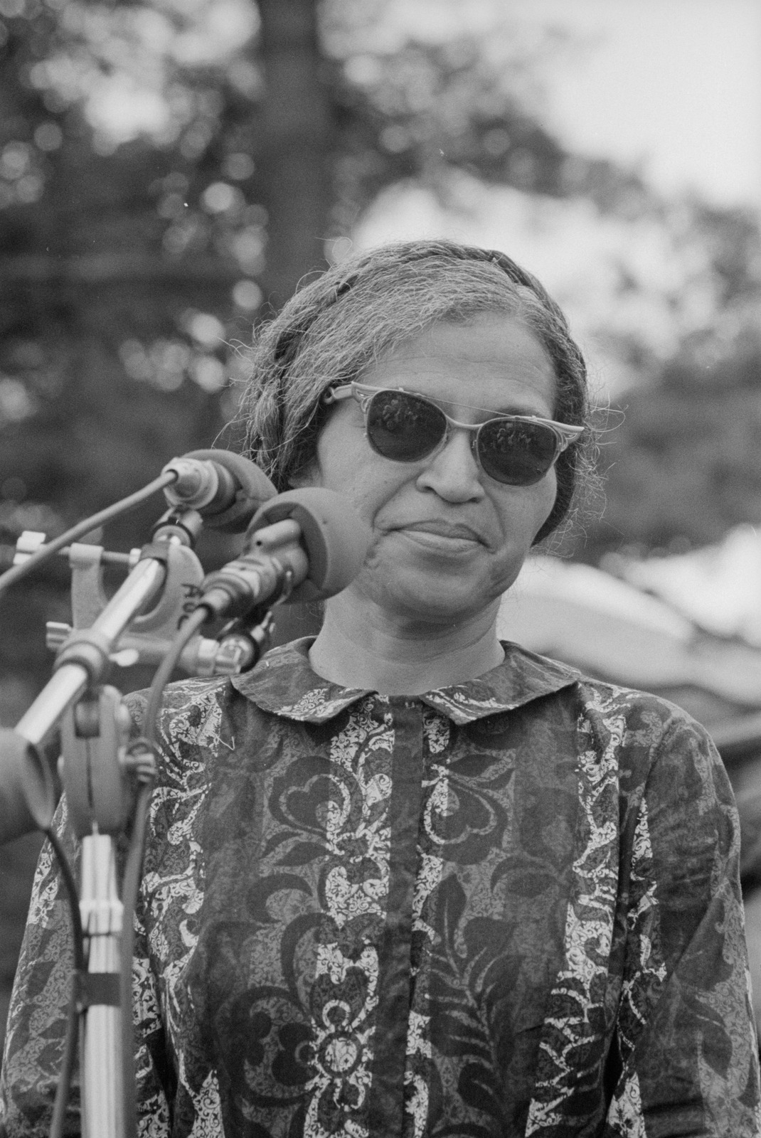 Rosa Parks speaking at a 1968 rally, standing behind several microphones.